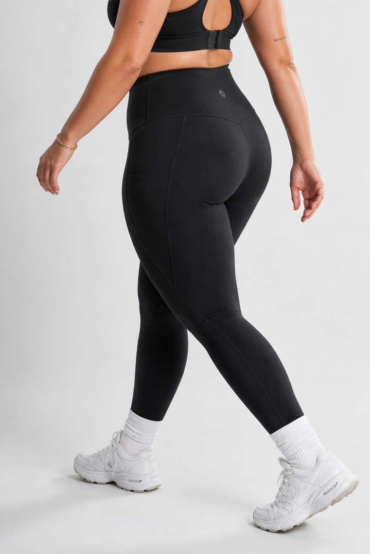 Person wearing black leggings and white sneakers on a plain background